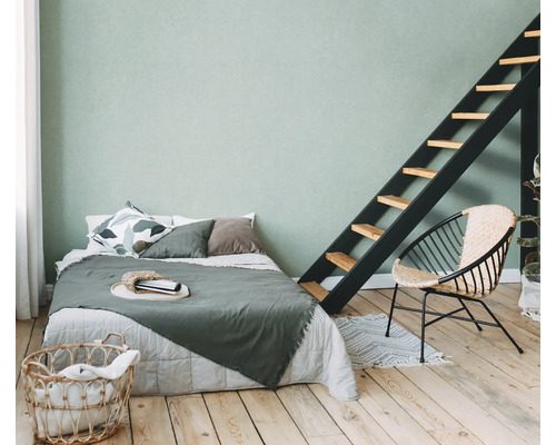 Lichte slaapkamer met bed, ladder, stoel en wasmand op houten vloer