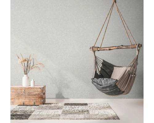 Hangstoel met kussens, kist en vloerkleed in een lichte kamer