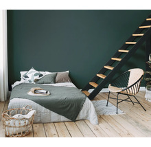 Slaapkamer met bed, ladder en rotan stoel op houten vloer