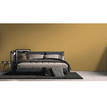 Slaapkamer met bed, nachtkastje en tapijt voor een muur