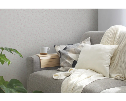 Woonkamer met grijze bank, kussens, deken, drankhouder en behang met patroon