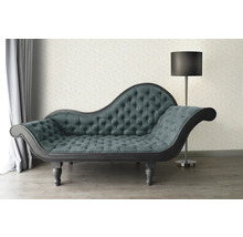 Chaise longue met knoopsluiting en staande lamp in een lichte kamer.