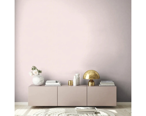 Woonkamer met roze muur, dressoir, tafellamp en decoratie