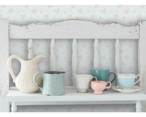 Decoratieve scène met verschillende kannen en kopjes op een witte plank tegen een bloemenbehang.