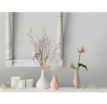 Woonkamer scène met bloemdecoraties, kaarsen en een fotolijst tegen een patroonbehang