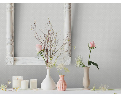 Woonkamer scène met bloemdecoraties, kaarsen en een fotolijst tegen een patroonbehang