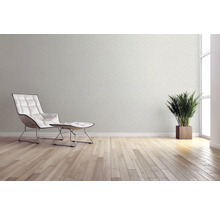 Woonkamer met behangmotief, fauteuil, voetenbank, kamerplant en houten vloer voor een heldere en vriendelijke sfeer.