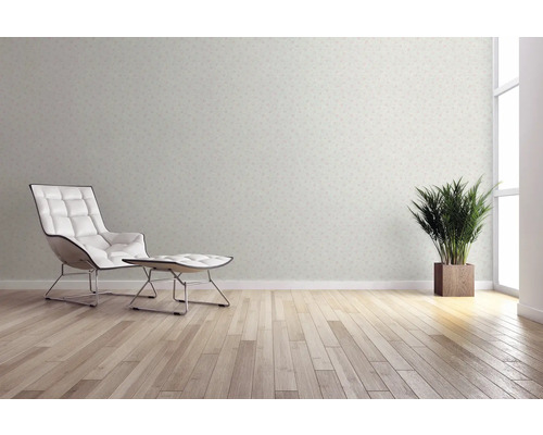 Woonkamer met behangmotief, fauteuil, voetenbank, kamerplant en houten vloer voor een heldere en vriendelijke sfeer.