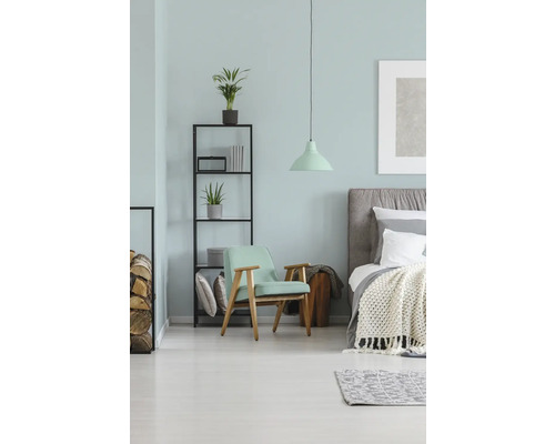 Slaapkamer met bed, fauteuil, rek en lamp