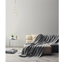 Woonkamer met bank, deken, tafel en lamp
