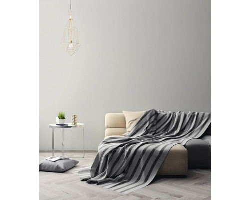 Woonkamer met bank, deken, tafel en lamp