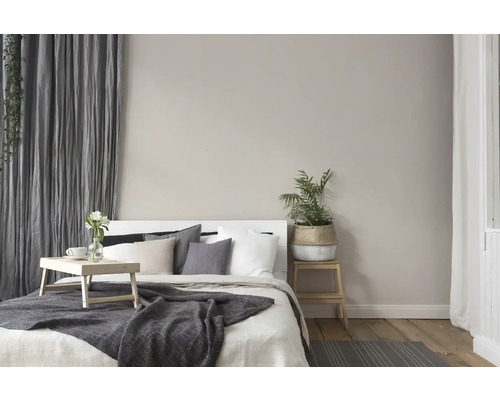 Lichte slaapkamer met bed, kussens, deken, gordijnen en kamerplanten