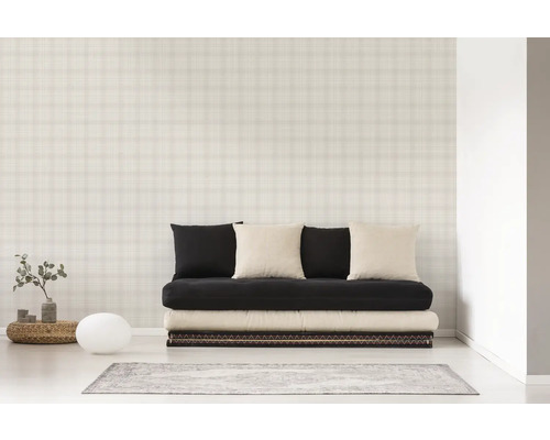 Een kamer met een bank, kussens en een behang met ruitpatroon.