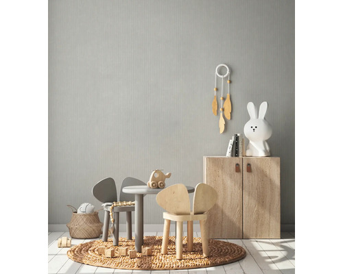 Lichte kinderkamer met kindermeubels, speelgoed en een subtiel patroonbehang.