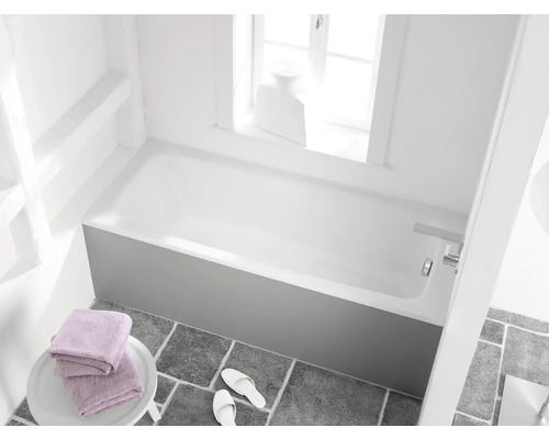 Badkamer met ligbad, handdoeken en badslippers op grijze tegelvloer