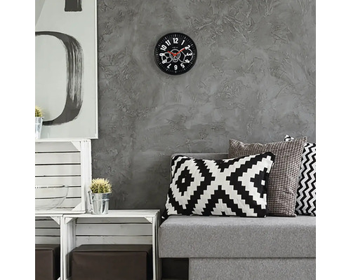 Woonkamer met grijze bank, kussens en wandklok met zichtbaar uurwerk