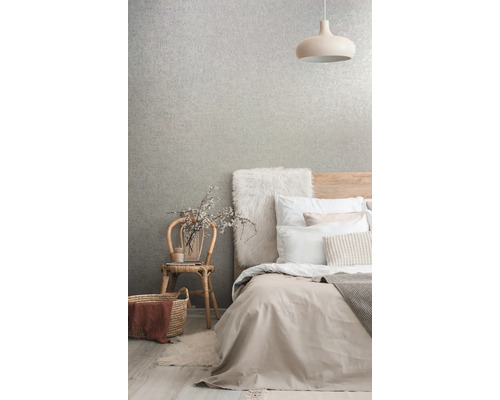 Slaapkamer met bed, lamp, stoel en behang met patroon voor een lichte en georganiseerde sfeer.