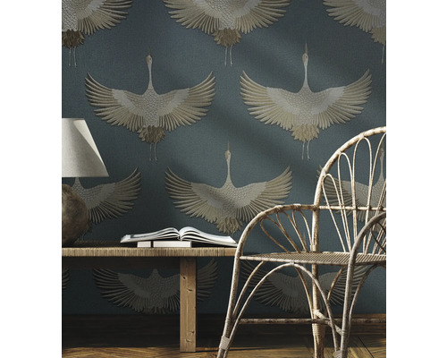 Scene met een rotan stoel, een houten tafel met boek en een behang met kraanvogelpatroon.