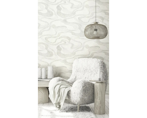 Woonkamer met patroonbehang, fauteuil en hanglamp