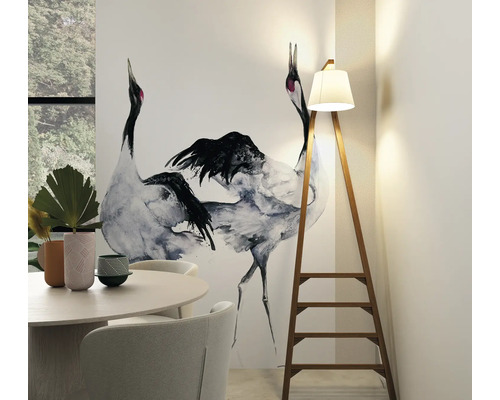 Woonkamer met eettafel, stoelen, behang met kraanvogelmotief en staande lamp in de vorm van een ladder