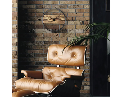 Woonkameropstelling met een wandklok met houten details en een gestoffeerde fauteuil voor een bakstenen muur.