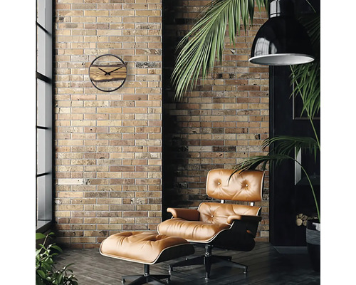 Woonkamer met bakstenen muur, fauteuil met voetenbank, hanglamp en houten wandklok