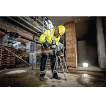 Een bouwvakker in werkkleding gebruikt een haakse slijper op een bouwplaats