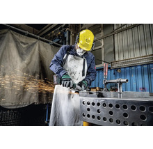 Een arbeider met veiligheidshelm, gehoorbescherming, ademhalingsmasker en schort slijpt metaal met een haakse slijper, waarbij vonken vrijkomen.