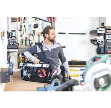 Man met gereedschapstas in werkplaats