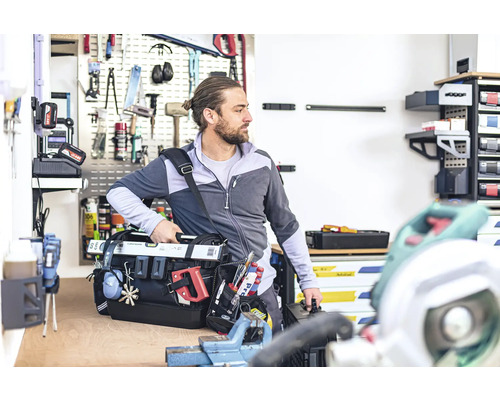 Man met gereedschapstas in werkplaats