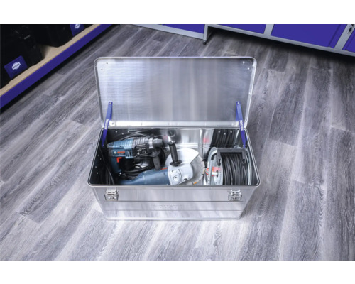 Geopende aluminium gereedschapskist met boormachine, haakse slijper en kabelhaspel