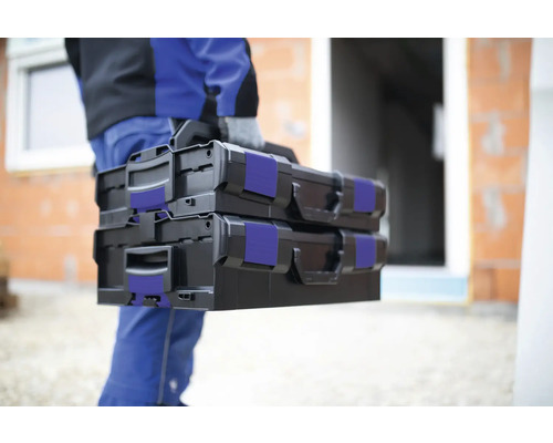 Een persoon draagt twee zwarte gereedschapskoffers.