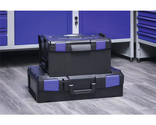 Twee zwarte gereedschapskoffers met blauwe sluitingen gestapeld voor een blauwe werkplaatskast.