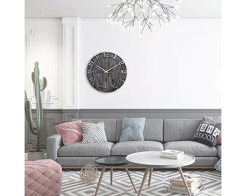 Woonkamer met grijze bank, salontafel en wandklok