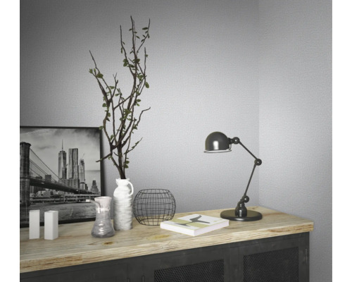 Decoratieve stilleven compositie op een dressoir met een zwart-wit foto, vazen, een plant, een boek en een bureaulamp.