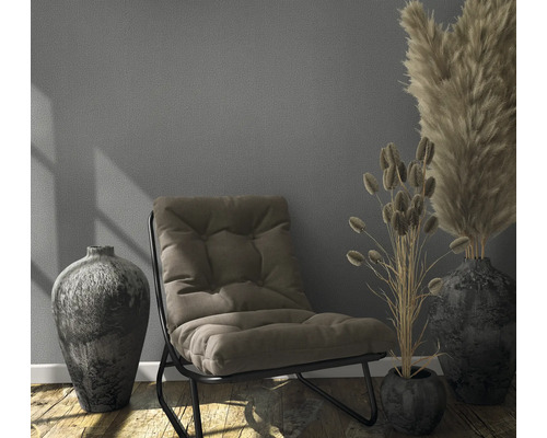 Interieurscène met fauteuil, vazen en droogbloemen op houten vloer voor een wand.