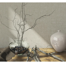Decoratieve opstelling met glazen vaas, takken en decoratieve ballen op een houten tafel.