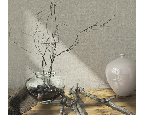 Decoratieve opstelling met glazen vaas, takken en decoratieve ballen op een houten tafel.