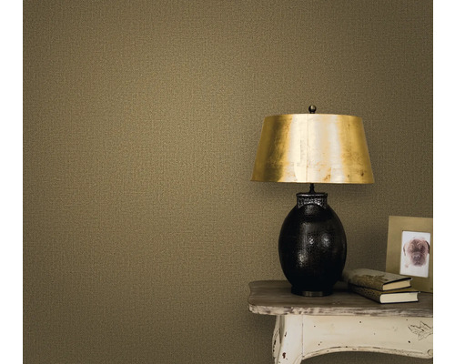 Close-up van een muur met een textielbehang, een nachtkastje, een lamp, een fotolijst en boeken.