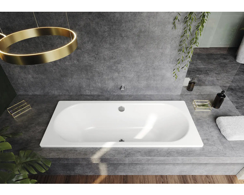 Rechthoekig bad in een modern ontworpen badkamer met grijze tegels en gouden accenten.