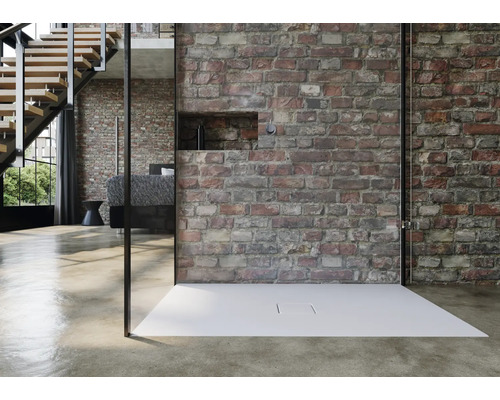 Inloopdouche met vlakke douchebak voor een bakstenen muur in een modern ingerichte ruimte.