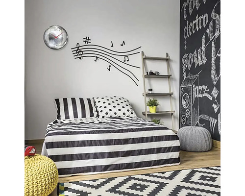 Slaapkamer met beddengoed met streepmotief, muursticker met muzieknoten en wandklok met spiegelballen