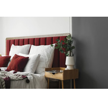 Slaapkamer met bed, rood hoofdeinde, houten nachtkastje en decoratie