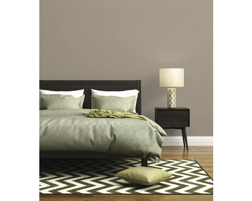 Slaapkamer met bed, nachtlamp en patroonte tapijt