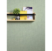 Decoratieve plank aan een gestructureerde muur met plant, notitieblokken en afbeelding.
