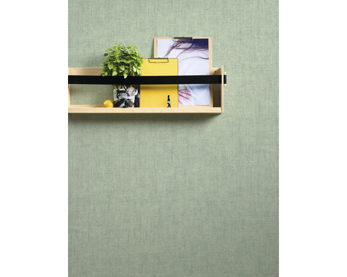 Decoratieve plank aan een gestructureerde muur met plant, notitieblokken en afbeelding.