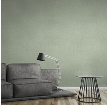 Woonkamer met groene textielbehang, bank, lamp en tafel