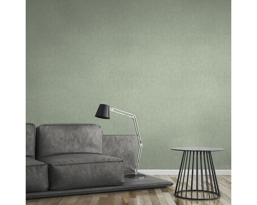 Woonkamer met groene textielbehang, bank, lamp en tafel