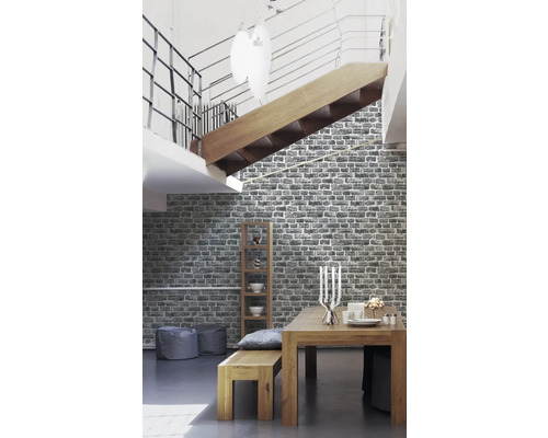 Woonkamer met eettafel, bank, rek en behang met steenmotief.