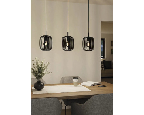 Drie metalen hanglampen boven een eettafel.